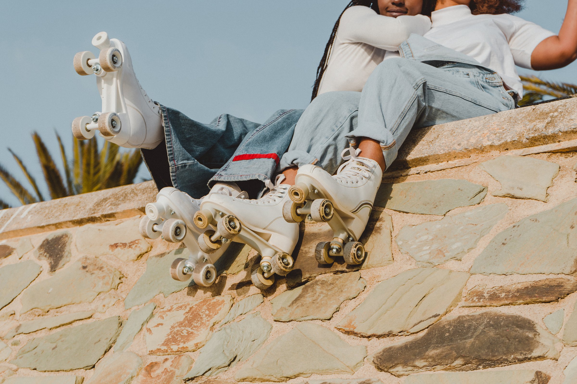 Two Teen Girls in Roller Skates Sitting and Hugging Outdoors